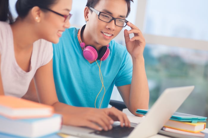 Two college students sharing a laptop. 