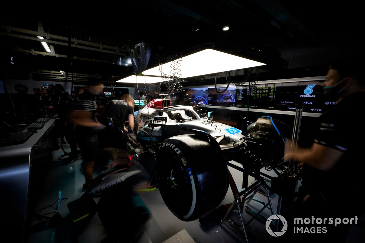 Mechanics work on the George Russell Mercedes W13 in the garage