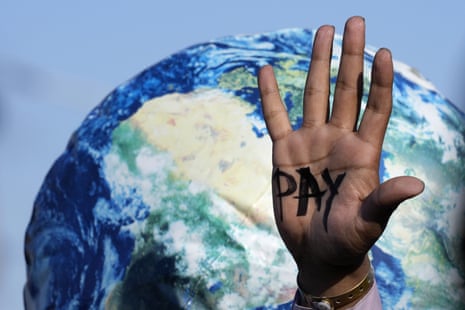 A hand reads “pay” as one of the protests over the course of the summit calling for funding for loss and damage.