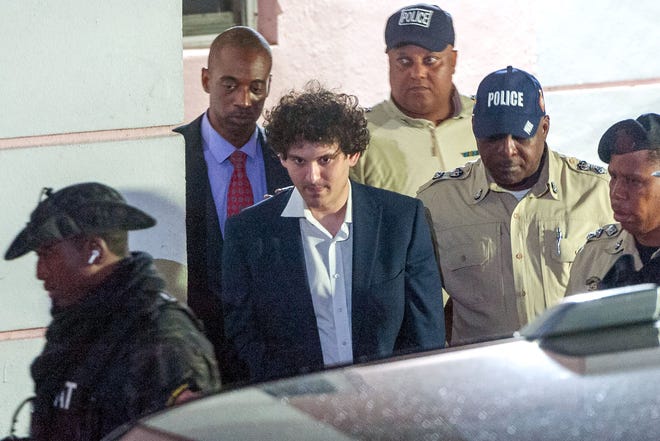 FTX founder Sam Bankman-Fried (C) is led away handcuffed by officers of the Royal Bahamas Police Force in Nassau, Bahamas on Dec. 13, 2022. Disgraced Bankman-Fried is accused of committing one of the biggest financial frauds in US history.