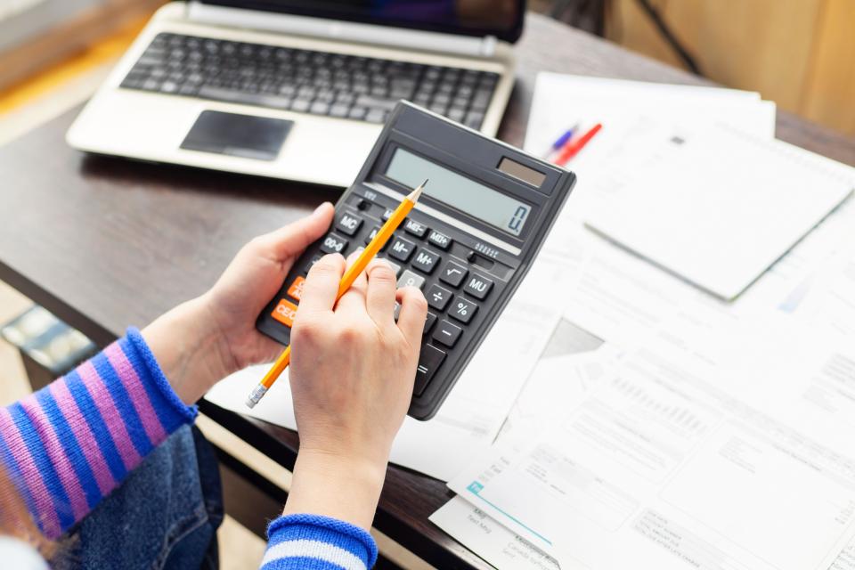 Woman using calculator for calculate domestic bills for paying taxes