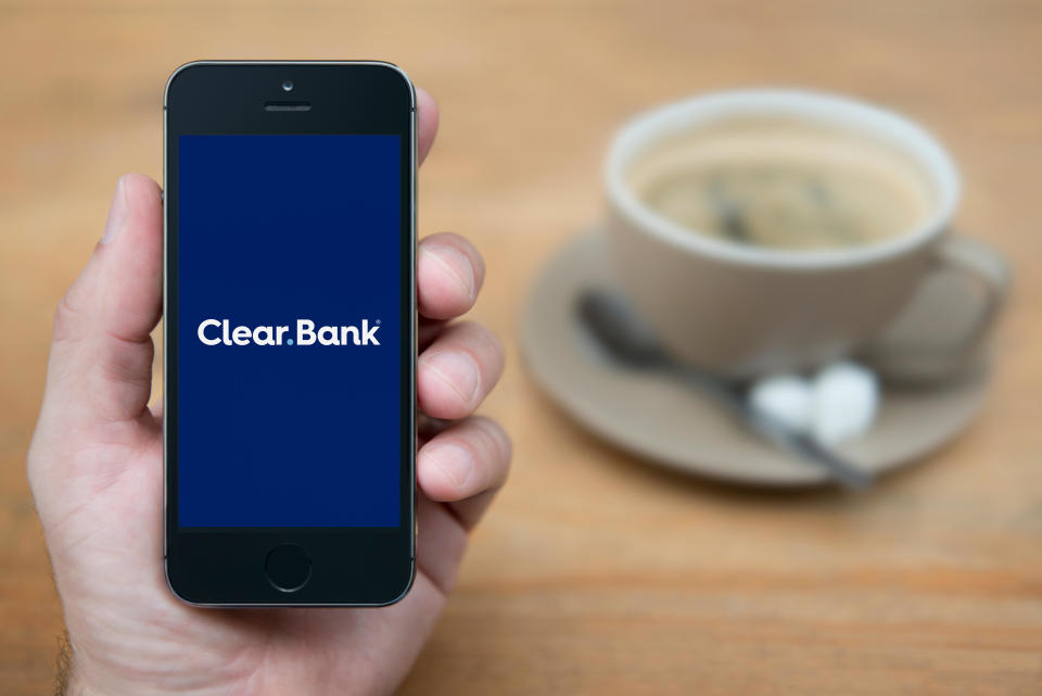 A man looks at his iPhone which displays the ClearBank logo (Editorial use only).