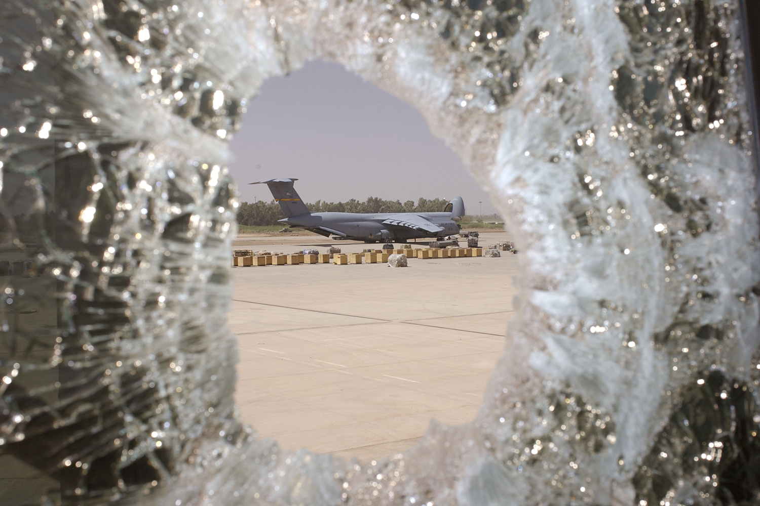 U.S. Air Force transport plane shown through shattered glass at Baghdad airport