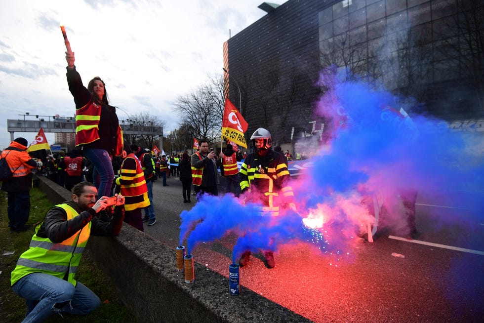 CGT unionists march with flares and banners on the ring road in Paris on March 17, 2023, as they block the traffic to protest, a day after the French government pushed a pensions reform through parliament without a vote, using article 49,3 of the constitution.