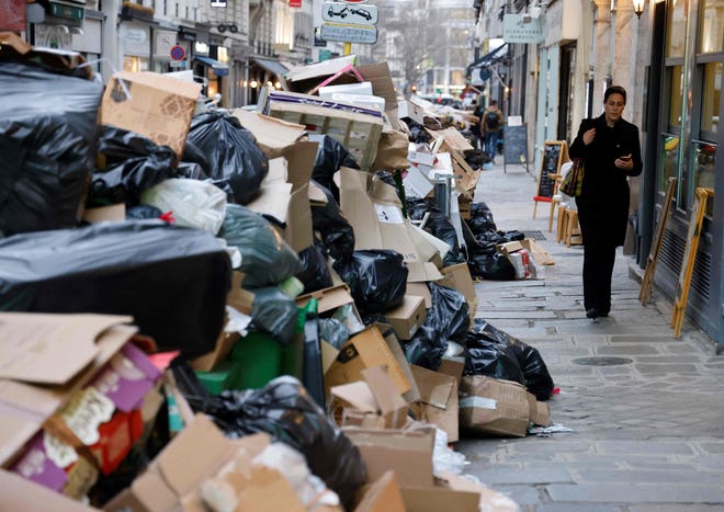 A woman walks past a pile of garbage bags in Paris on March 20, 2023.