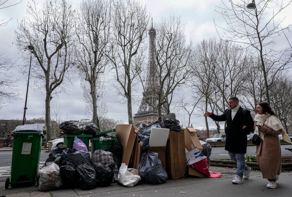 People walk past a pile of garbage near the Eiffel Tower in Paris, March 12, 2023, as strikes continue with uncollected garbage piling higher by the day.