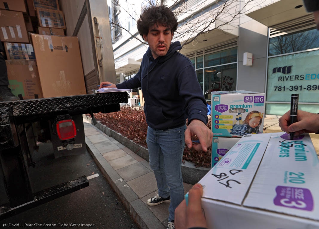 Man reaching for box to put on truck being loaded on city street (© David L. Ryan/The Boston Globe/Getty Images)