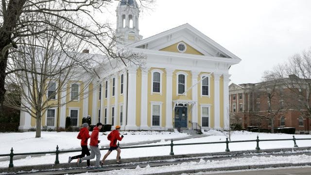 Runners make their way along a sidewalk on the campus of Wheaton College, in Norton, Mass.