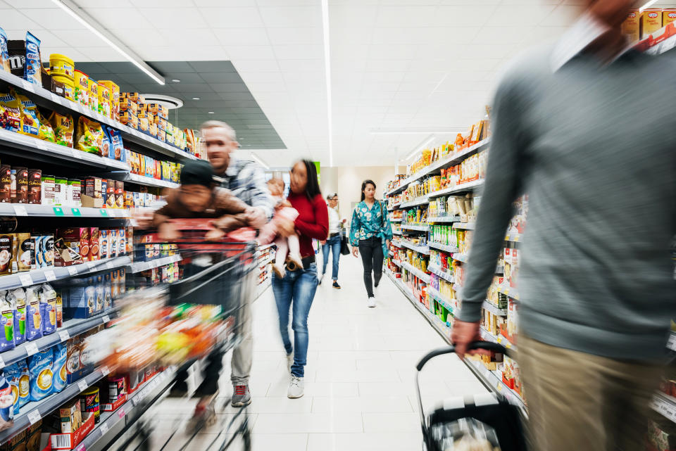 A busy supermarket aisle with various customers buying groceries