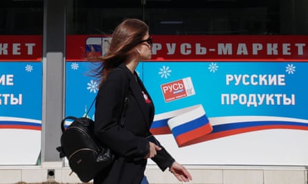 A woman walks past a Russian supermarket in Limassol