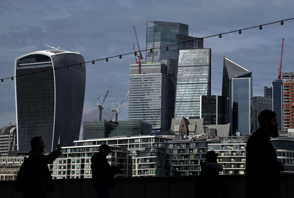 People walk with skyscrapers in the City of London financial district seen behind in London, Britain, March 16, 2023. REUTERS/Toby Melville