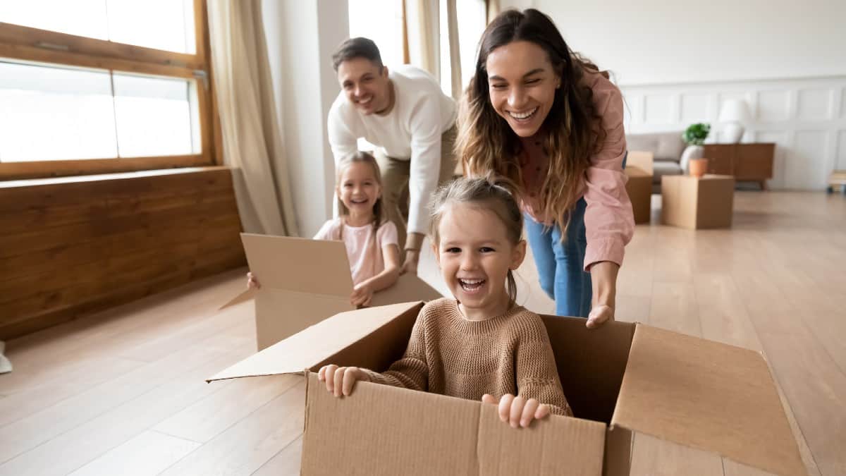 Happy parents playing with little kids riding in box