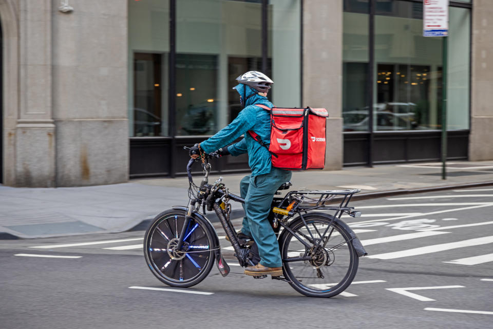 Manhattan, New York, NY, USA - July 10th 2022: Fast food delivery person with crash helmet on a electric bike and with a red bag on Broadway
