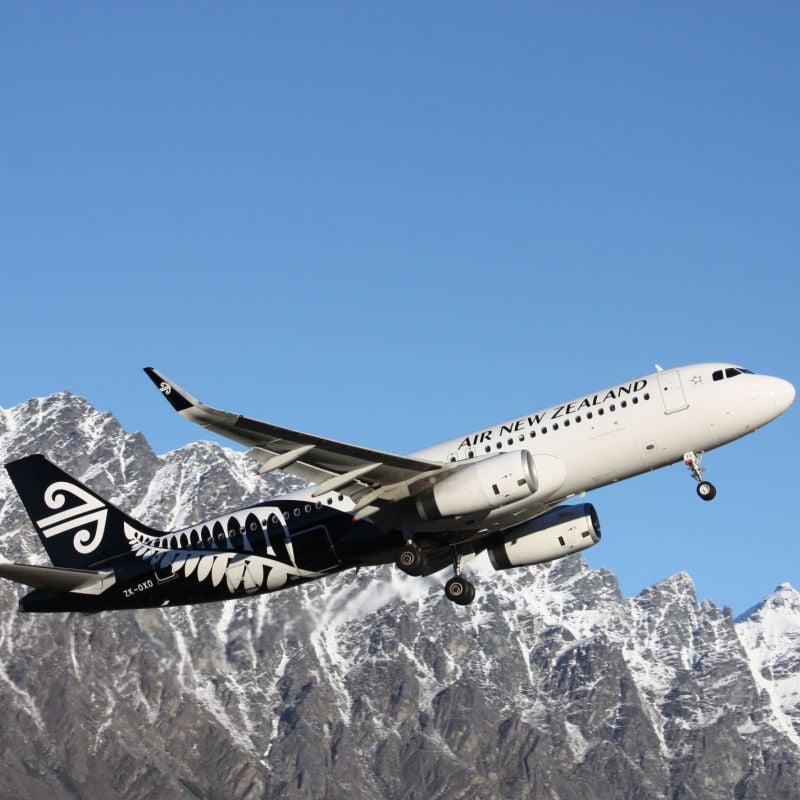 An air New Zealand plane flies over rocky mountains