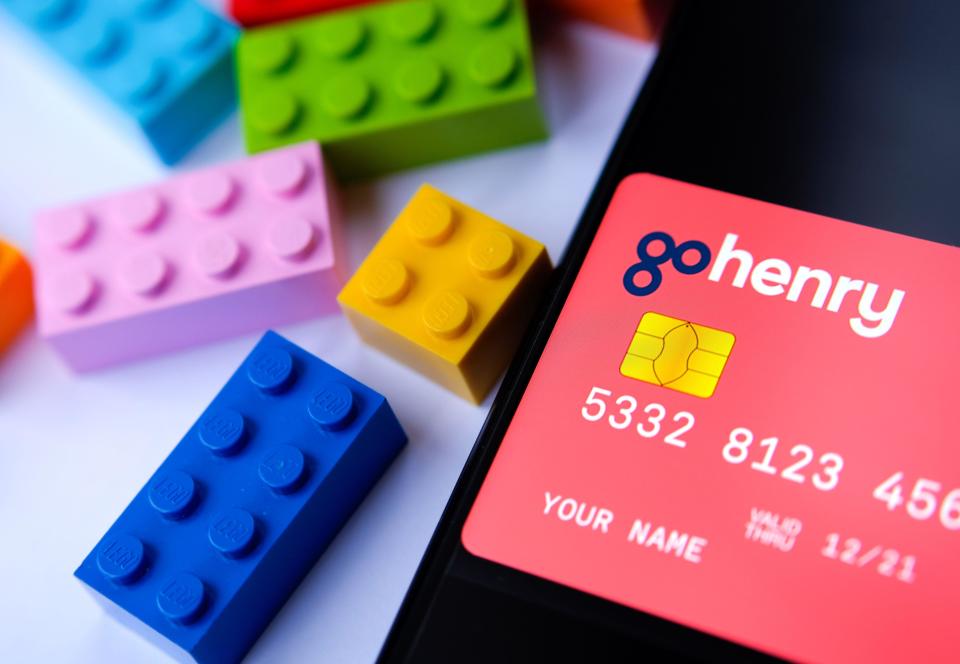 GoHenry card on the smartphone screen and lego bricks next to it. Card with dummy numbers. No sensitive info. Selective focus.