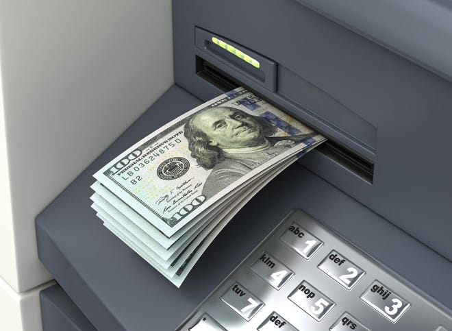 An ATM is serving up a wad of hundred-dollar bills.