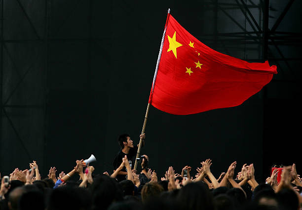BEIJING - OCTOBER 02:  A Chinese teenager waves a national flag during a rock-and-roll festival to mark  Chinese National Day on October 2, 2005 in Beijing, China. Various activities are being held in China to mark the National Day.  (Photo by Guang Niu/Getty Images)