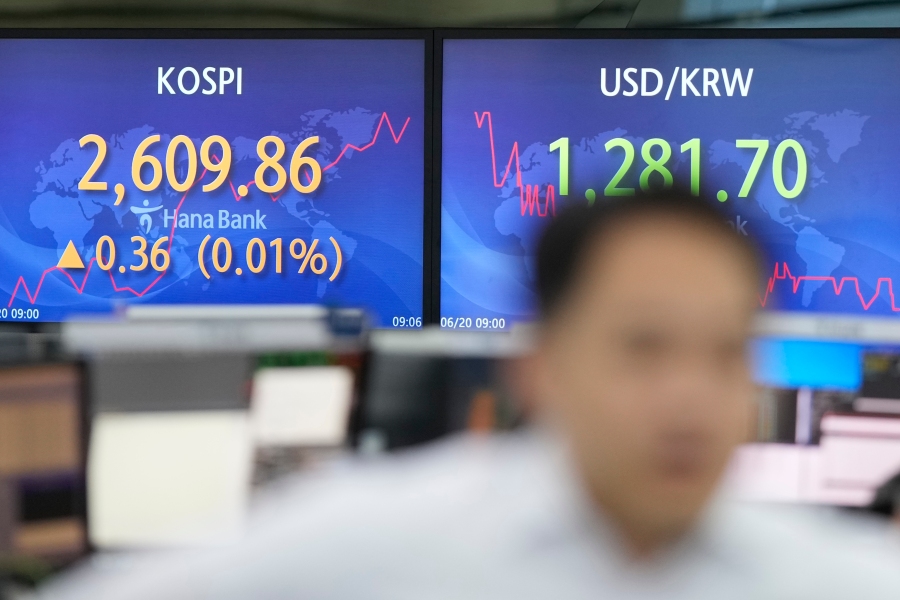 A currency trader walks by the screens showing the Korea Composite Stock Price Index (KOSPI), left, and the foreign exchange rate between U.S. dollar and South Korean won at a foreign exchange dealing room in Seoul, South Korea, Tuesday, June 20, 2023. Asian shares mostly declined Tuesday as some investors took a wait-and-see attitude after U.S. markets were closed for a national holiday. (AP Photo/Lee Jin-man)
