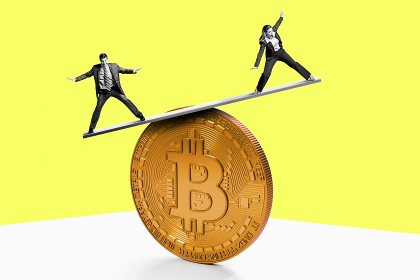 A man and a woman attempt to gain their balance on top of a Bitcoin