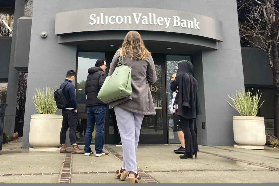 FILE - People stand outside a Silicon Valley Bank branch in Santa Clara, Calif., on March 10, 2023. California&#39;s bank regulator was too slow to see the growing risks at Silicon Valley Bank and did not act forcefully enough to get the bank to fix its problems, the regulator found in its own report issued Monday, May 8. (AP Photo/Jeff Chiu, File)