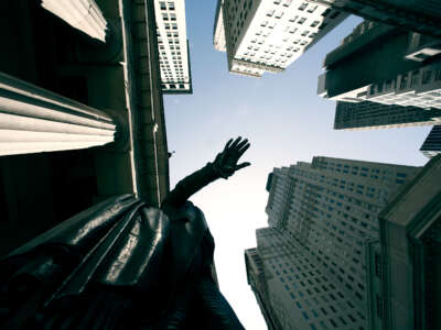 Looking up at buildings and hand of statue on Wall Street