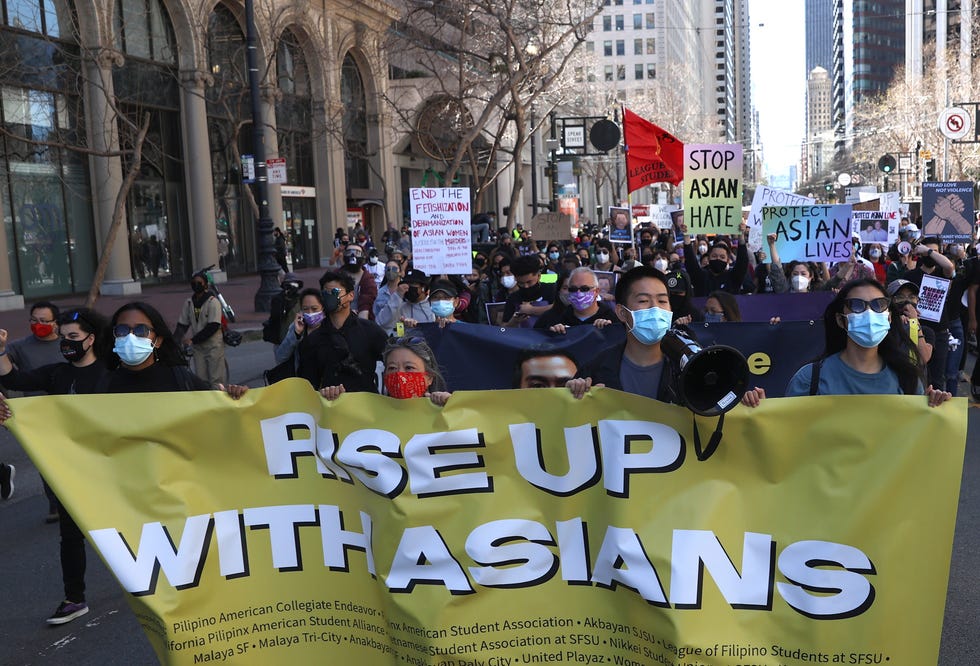 Protesters hold signs as they march along Market Street in San Francisco before a 2021 rally to show solidarity with Asian Americans.