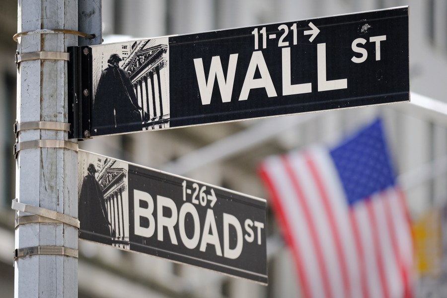 A U.S. Flag hangs in the background at the corner of Wall and Broad Streets in the heart of the Financial District in New York City, Tuesday, Aug. 1, 2023. Stocks are taking a step back Tuesday from their big surge for the year so far following a mixed set of earnings reports from U.S. companies. (AP Photo/J. David Ake)