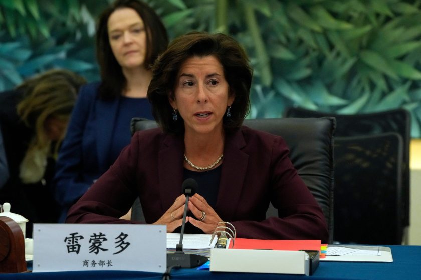 U.S. Commerce Secretary Gina Raimondo sits at a table in front of a name plate with Chinese lettering.