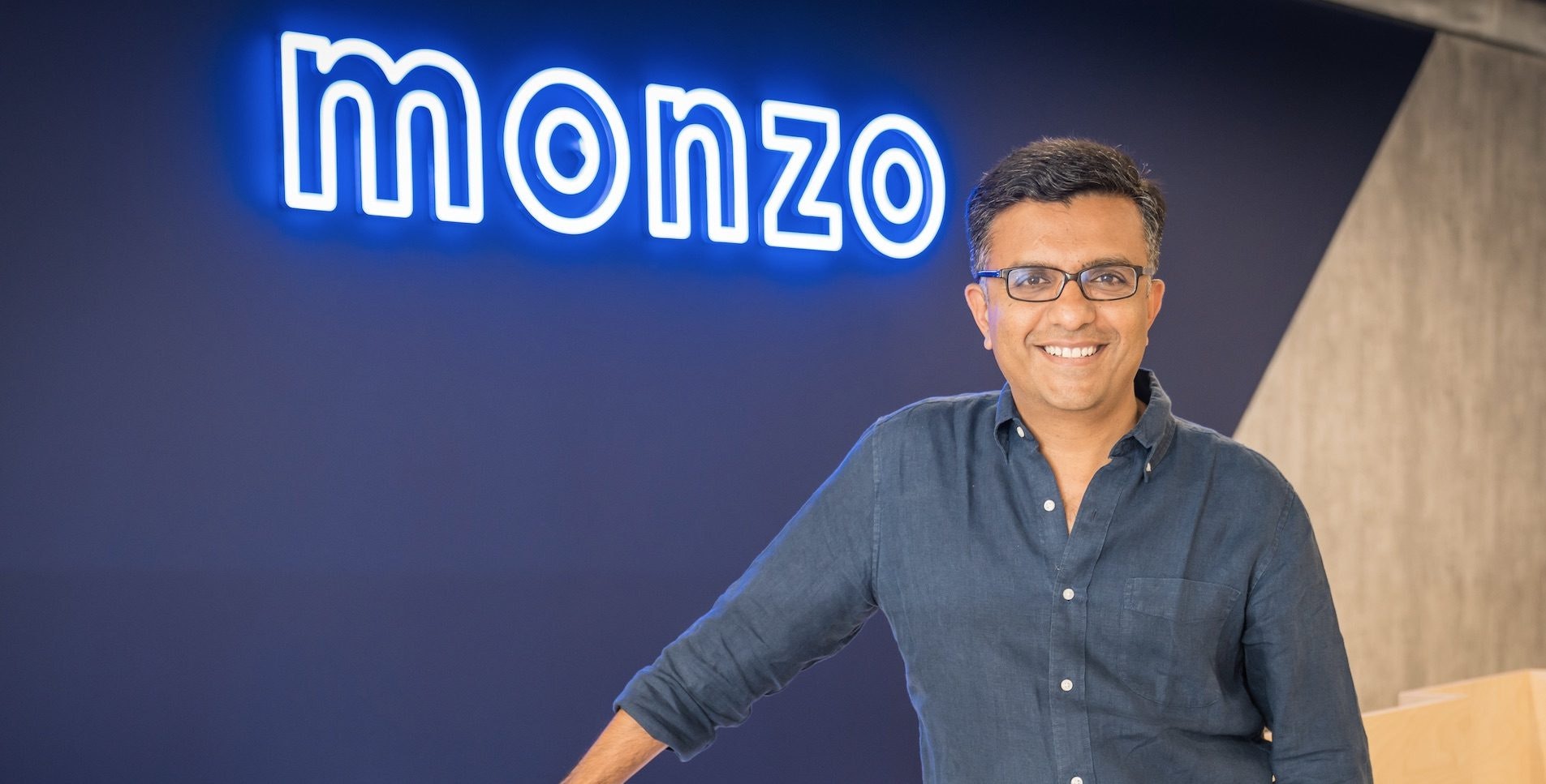 TS Anil, Monzo's Chief Executive Officer standing in front of a Monzo sign