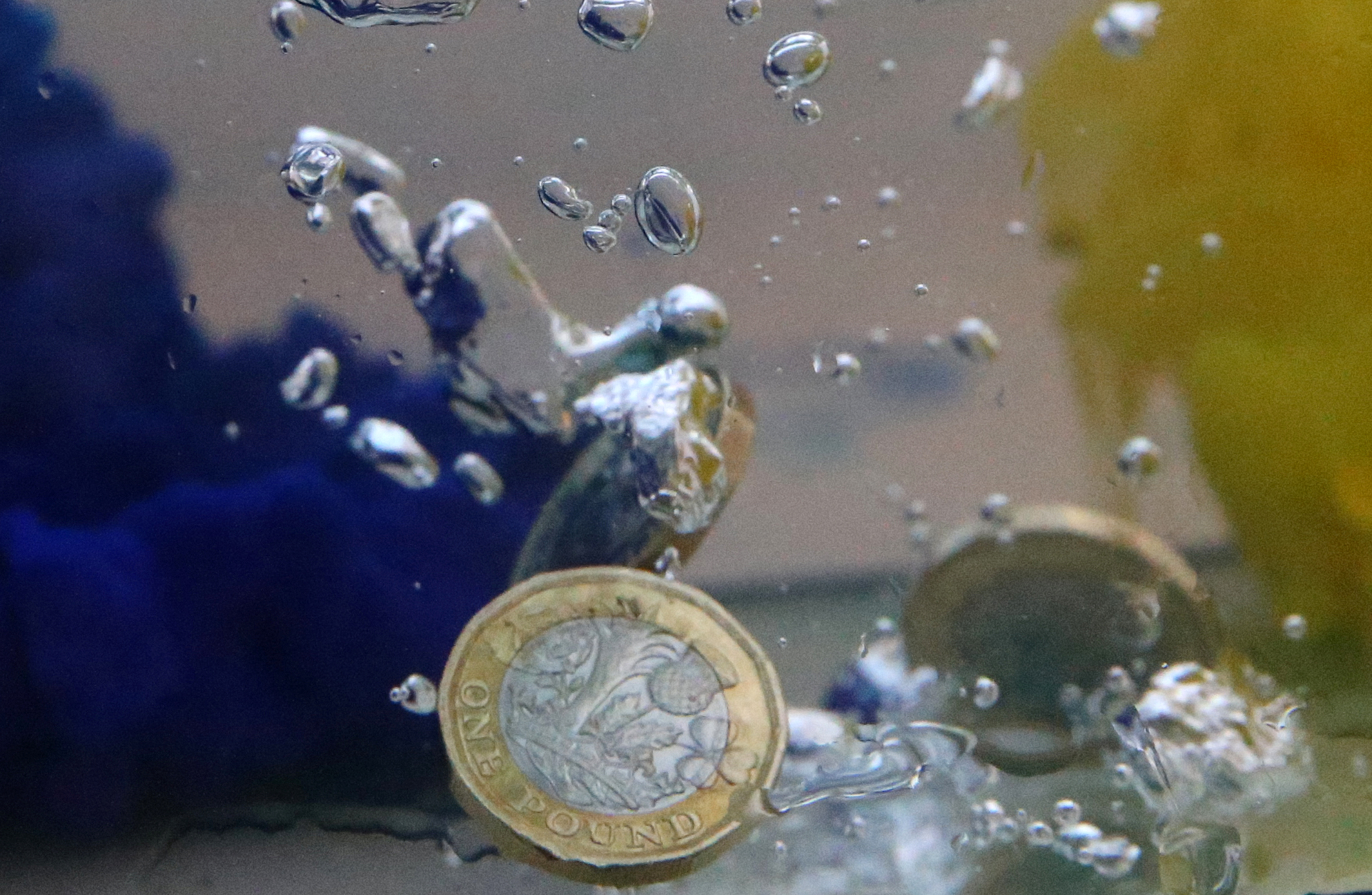 UK pound coins plunge into water coloured with the European Union flag colours in this illustration picture