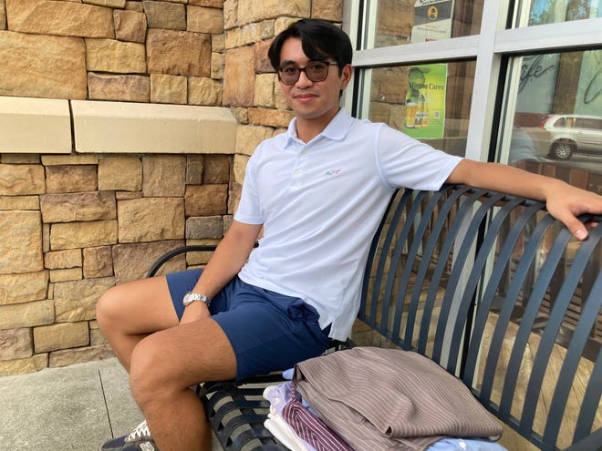 Patrick Macalintal, 21, sits with his newly thrifted clothes outside a Goodwill store in Raleigh, North Carolina's Brier Creek neighborhood on August 25, 2023. Macalintal said he tries to maintain the quality of his clothes, so that they'll last.