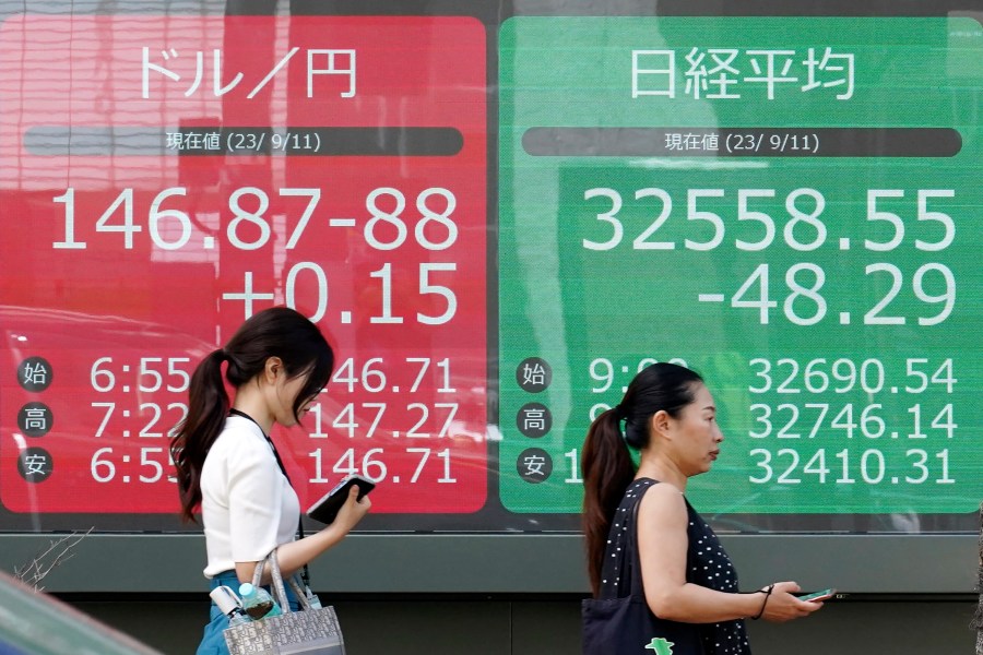 People walk in front of an electronic stock board showing Japan's Nikkei 225 index and U.S. dollar/Japanese yen exchange rate at a securities firm Monday, Sept. 11, 2023, in Tokyo. Stock prices were mostly higher in Asia on Monday as investors awaited U.S. inflation figures and China’s latest economic data. (AP Photo/Eugene Hoshiko)