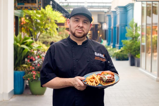 Chef Martin Andrade holding a Chili Relleno burger. He created the menu item for Eureka! and the restaurant launched the burger on Sept. 6, 2023.