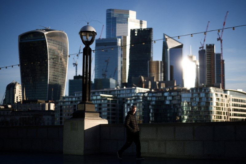 A person walks alongside the River Thames during sunrise in London