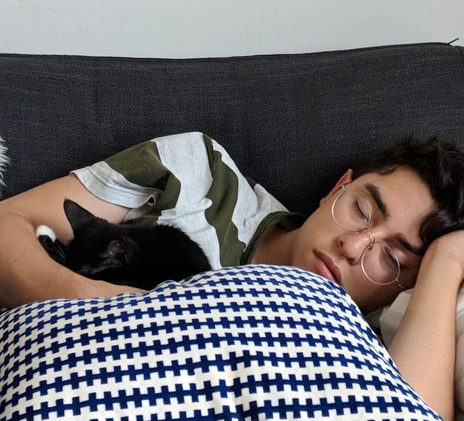 Jacob Mata snuggles with one of this three cats in his apartment near San Francisco's Outer Mission/Excelsior neighborhood.