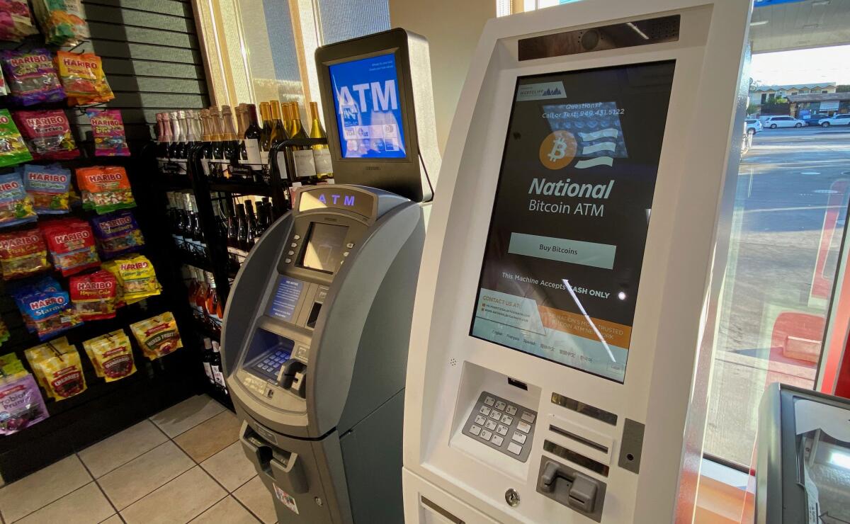 A Bitcoin ATM sits next to a regular cash ATM inside a store