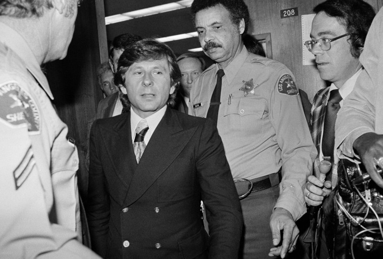 On this date in 1977: Movie director Roman Polanski walks past two Los Angeles County sheriffs' deputies as he leaves court proceedings in Santa Monica, Calif. Polanski was called to court to explain a recent trip to Europe, fleeing a 90-day sentence to prison for psychiatric tests relating to his earlier guilty plea to a sex crime involving a 13-year-old girl. The night before Polanski's sentencing hearing in 1978, he fled to Europe where he continued his career; he remains a fugitive of the U.S. justice system. 