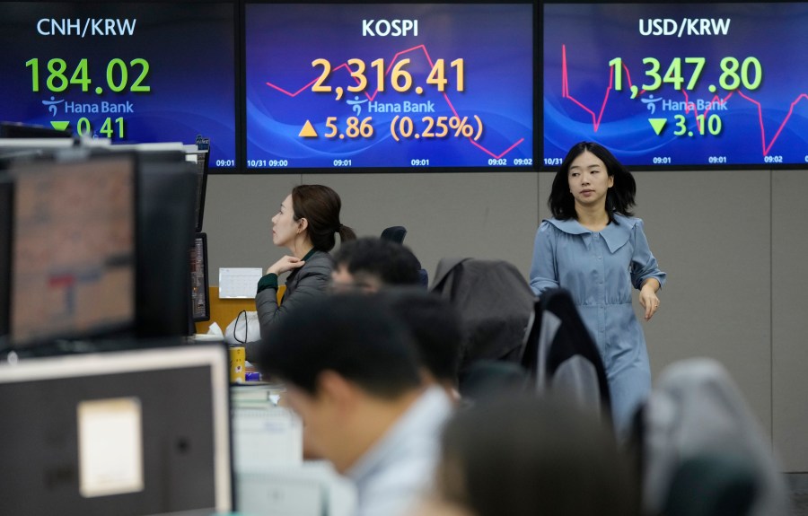 A currency trader passes by the screens showing the Korea Composite Stock Price Index (KOSPI), center, and the foreign exchange rate between U.S. dollar and South Korean won, right, at the foreign exchange dealing room of the KEB Hana Bank headquarters in Seoul, South Korea, Tuesday, Oct. 31, 2023. Asian shares were trading mostly lower Wednesday as investors looked ahead to a week that could see more swings in financial markets, including key reports on U.S. consumer confidence and the job market. (AP Photo/Ahn Young-joon)
