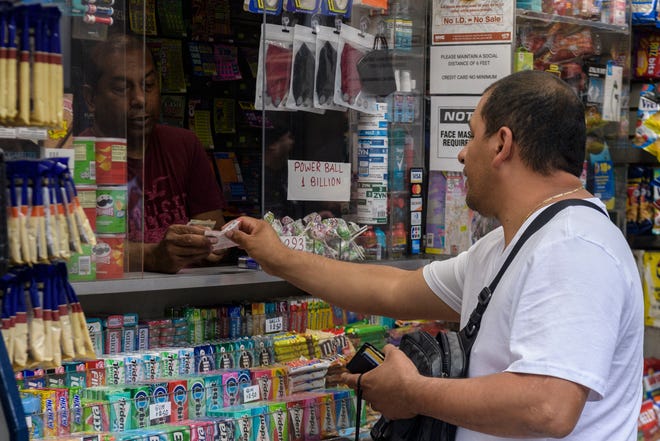 A person buys Powerball tickets at a news stand in New York City on July 19, 2023.