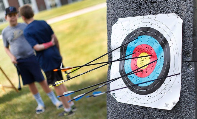 Young archers talk about their targets between shooting sessions at a summer archery camp in July.