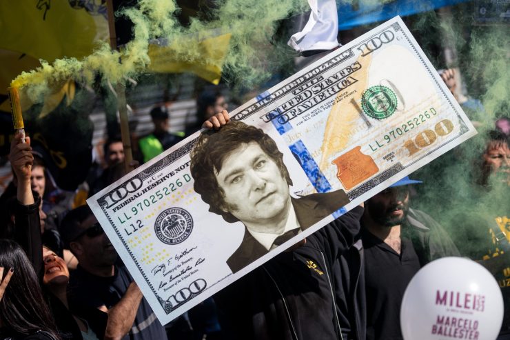 A supporter of Presidential candidate Javier Milei of La Libertad Avanza holds a giant fake $100 U.S. dollar bill with Milei's face where Benjamin Franklin's should be.