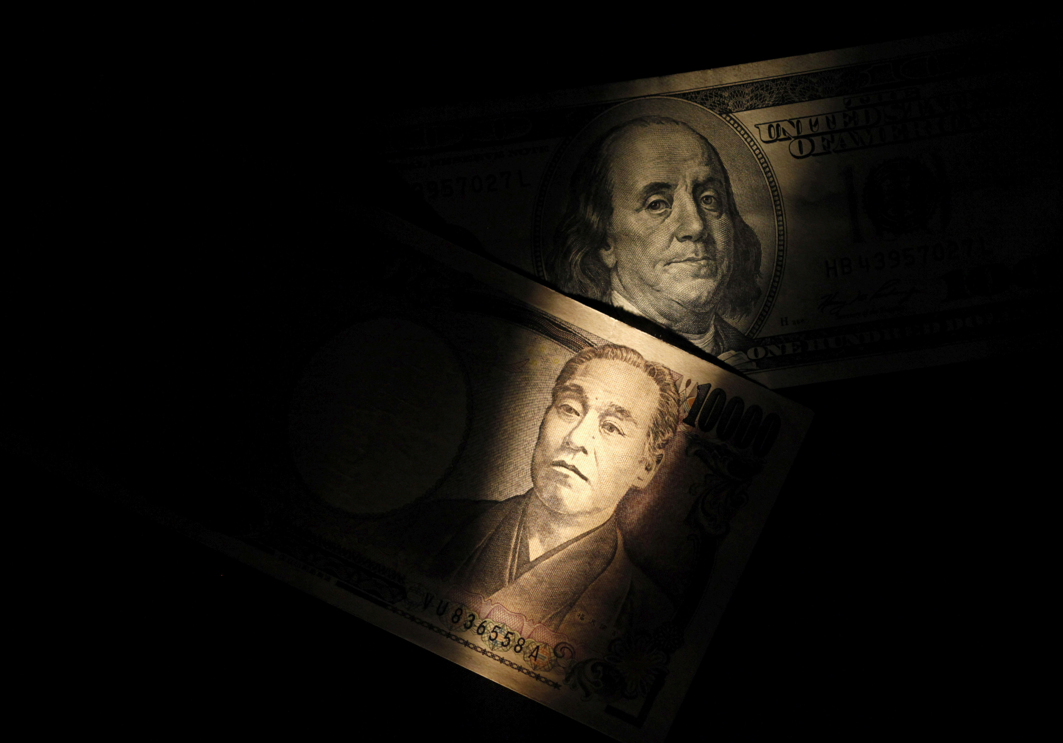 Light is cast on U.S. one-hundred dollar bill next to Japanese 10,000 yen note