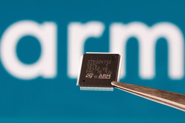 ARM company logo seen on STM32 microchip hold in tweezers and blurred ARM company logo on the background. London, United Kingdom, September 17, 2023