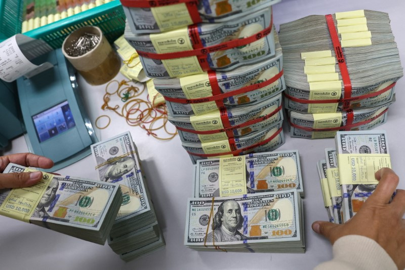 A bank employee gather U.S. dollar notes at a Kasikornbank in Bangkok