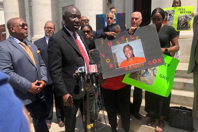 Attorney Benjamin Crump, foreground left, and Doreen Coleman, mother of Randy Cox, hold a poster of Cox outside a courthouse in New Haven, Conn., on Friday. Cox, who was being transported in a police van without seat belts, was paralyzed when the van braked suddenly. His family asked federal authorities Friday to file civil rights charges against the officers involved.