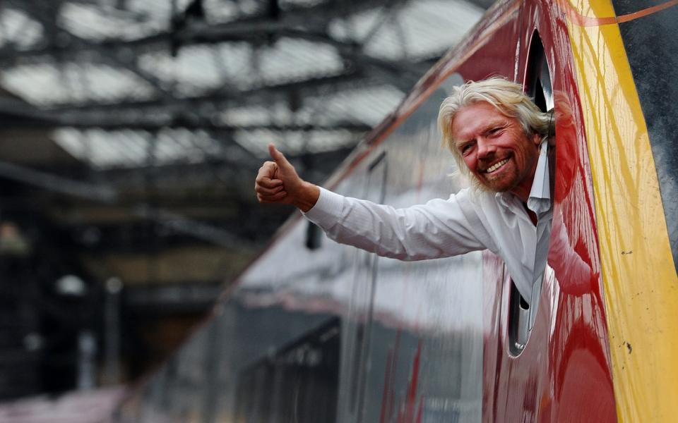 British entrepreneur Sir Richard Branson leans out of the window of the driver's cab on board a Virgin Pendolino train