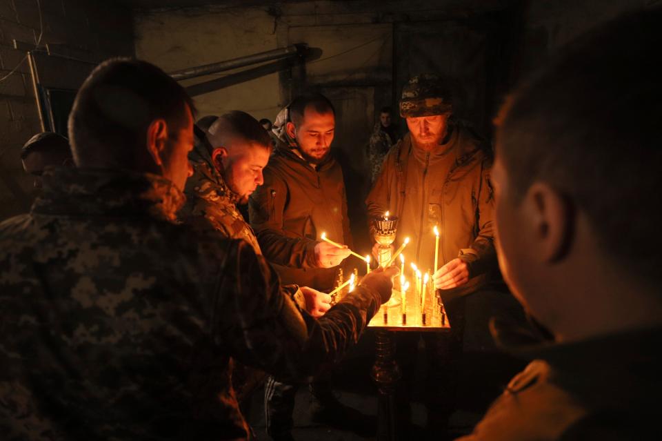 Ukrainian servicemen of the 72nd mechanized brigade light candles during the sacred liturgy before the upcoming Christmas at the frontline near Vuhledar, Ukraine (AP)