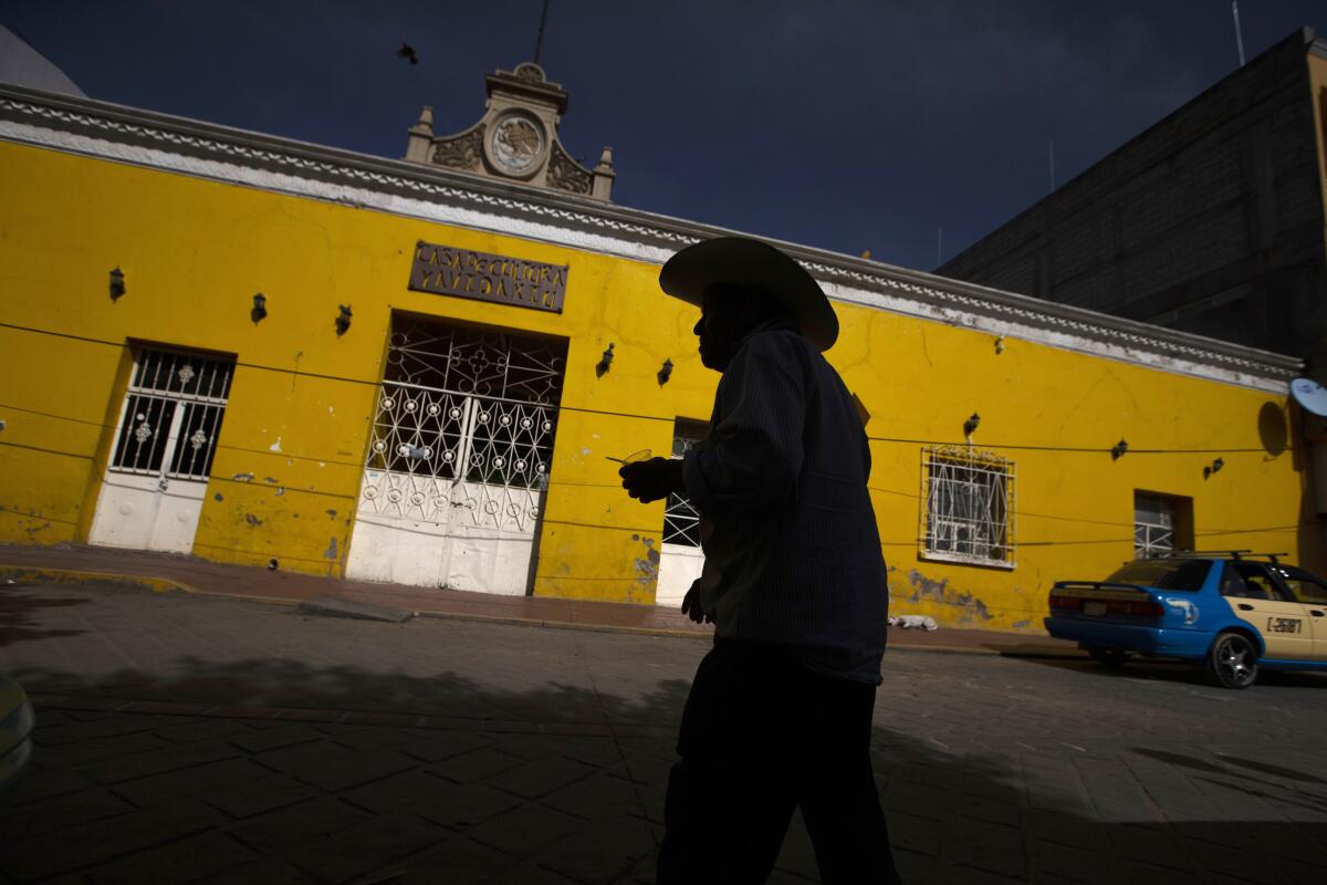 A man in silhouette walks past a building 