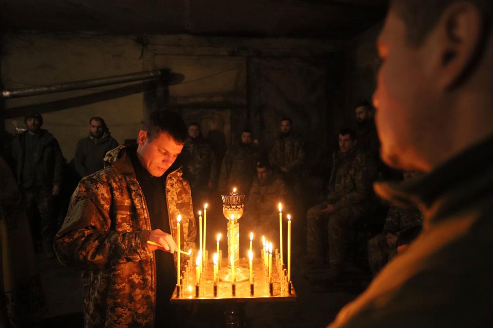 A Ukrainian serviceman of the 72nd mechanized brigade lights a candle (AP)