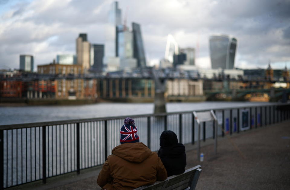 FTSE People sit alongside the bank of the River Thames with the City of London financial district in the background, in London, Britain, January 13, 2023. REUTERS/Henry Nicholls